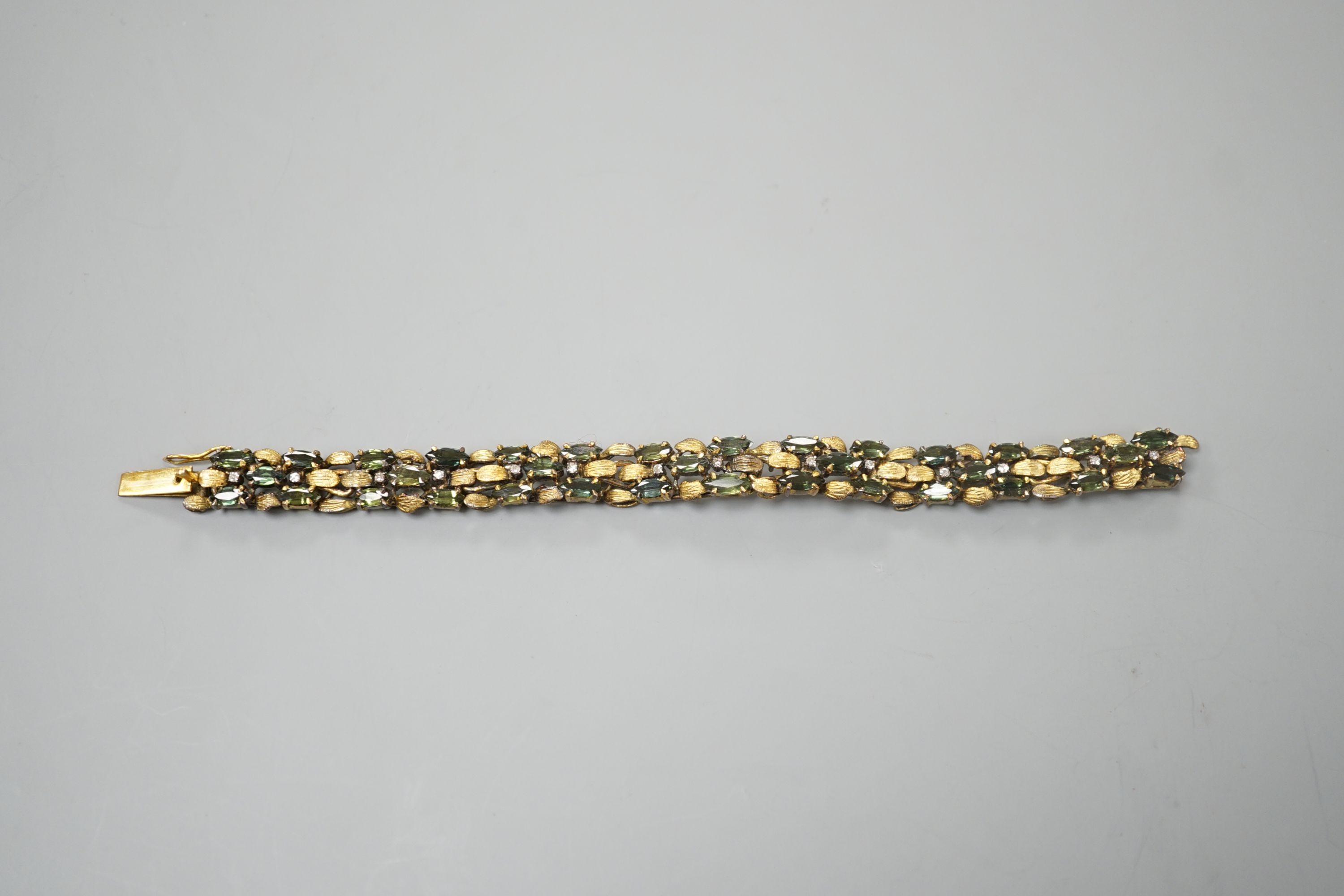 A modern yellow metal, multi green stone and multi diamond chip set bracelet, 16.5cm, gross weight 23.8 grams.